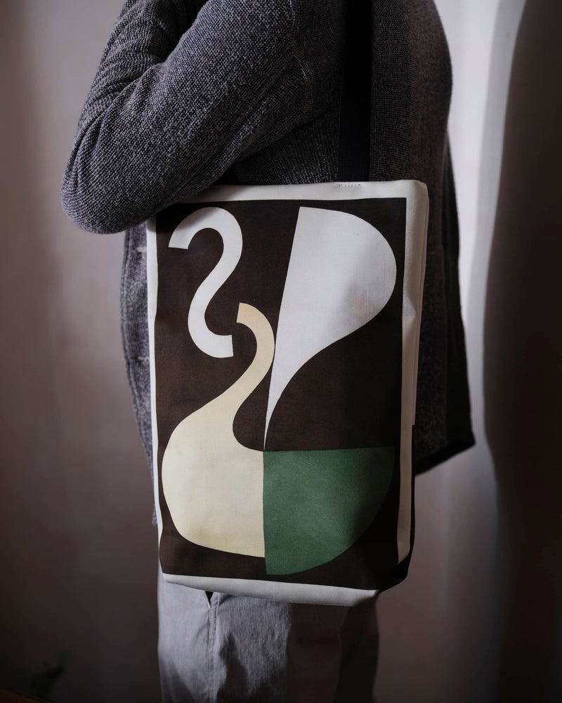Abstract art tote bag displaying a Sophie Taeuber Arp artwork worn my a male model, close up view.
