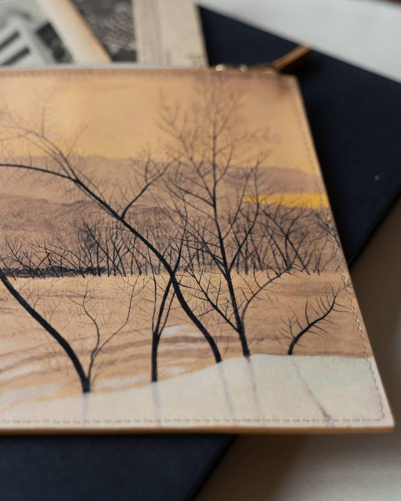 Close up of part of an art bag printed with a tree painting by Léon Spilliaert, laying on art books.