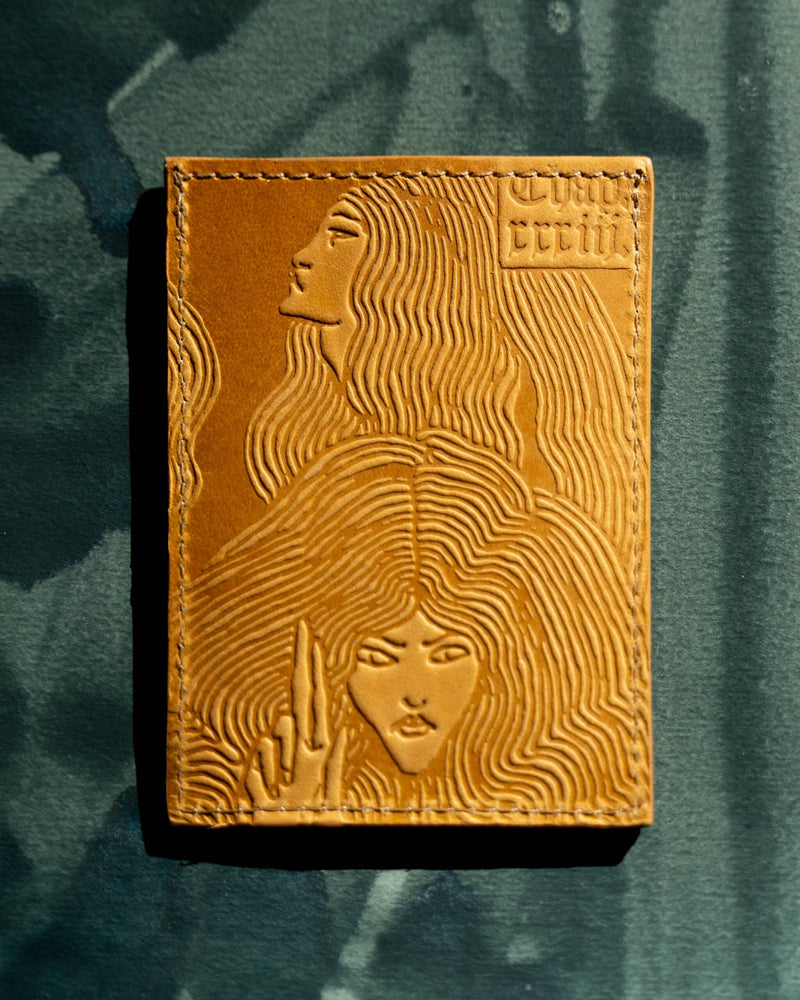 Handmade leather card wallet with witches artwork by Aubrey Beardsley on green painted background.