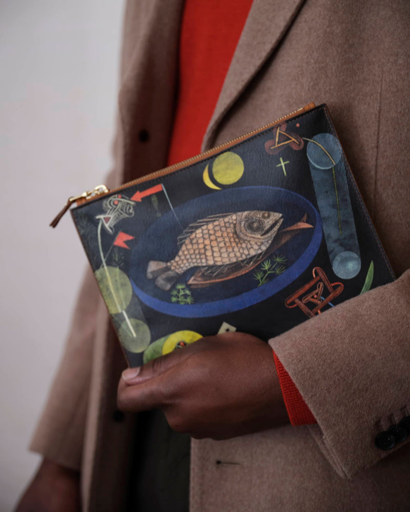 Unique bag with surrealist fish art by Paul Klee held by a male model in soft focus.