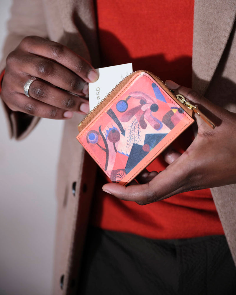 Model pulling a card out of a unique purse with a Paul Klee art print.