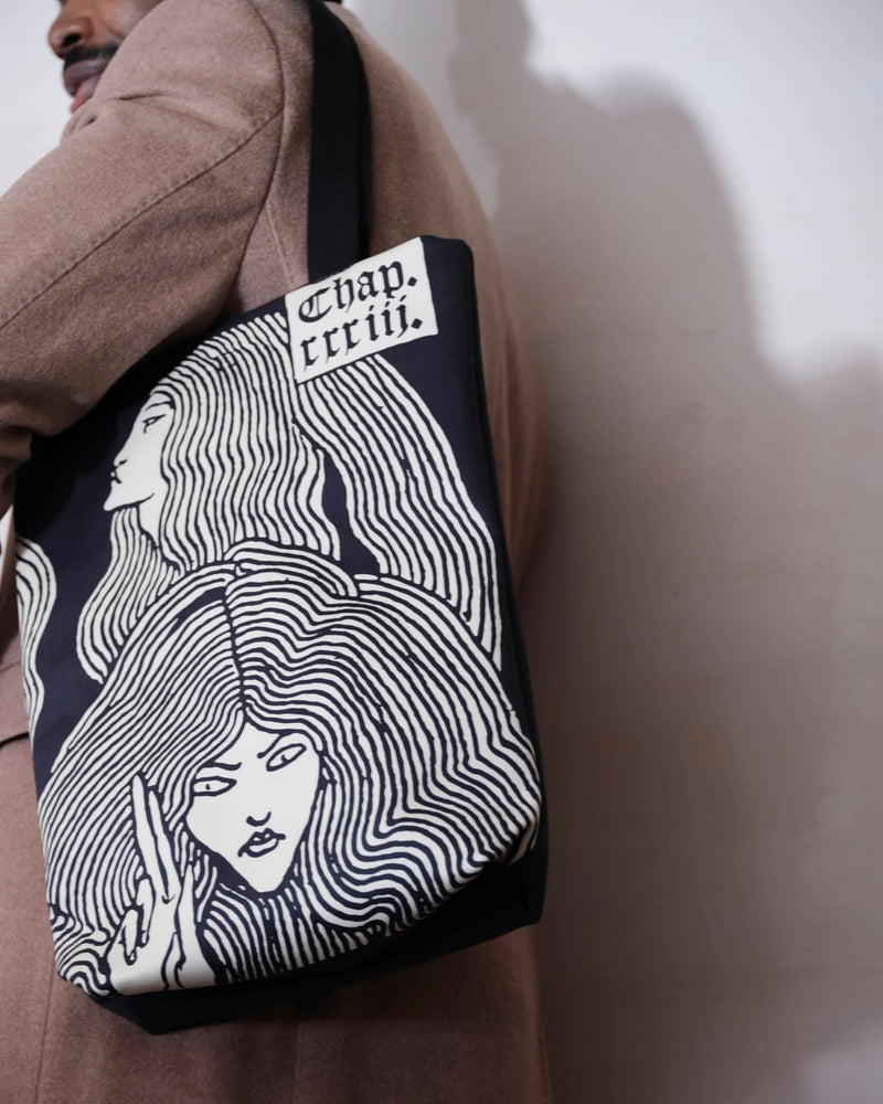 Close up of the unique witches bag design in cream and black with artwork by Aubrey Beardsley, worn be a male model.