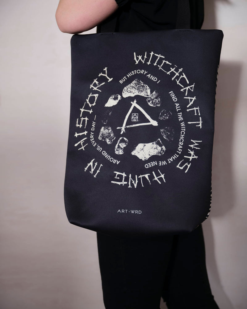 Close up of a unique witches bag design with a witches poem by Emily Dickinson, worn be a female model.