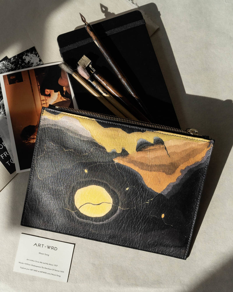 Unusual bag printed with Arthur Dove 'Me and The Moon' artwork on top of photos, a notebook and paint brushes. Next to it is a Moon Song artist and writer information card.