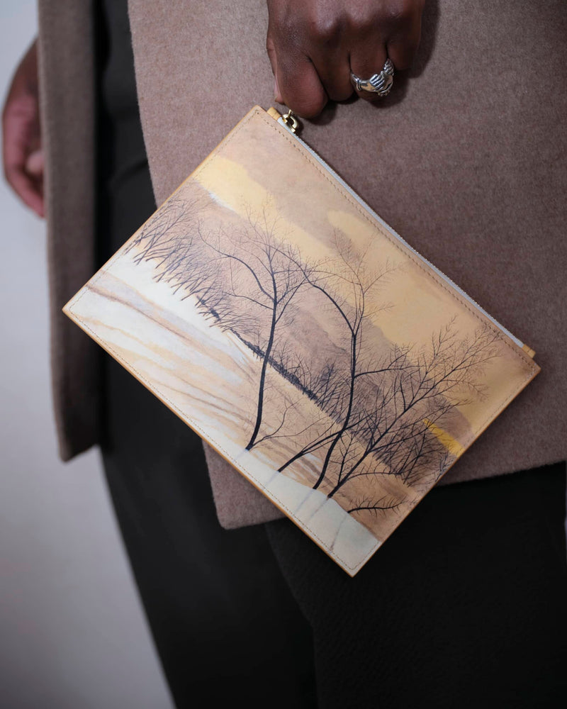 Art bag printed with tree painting by Léon Spilliaert carried hanging by the zip puller by a male model. 