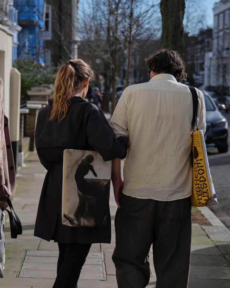 Two models wearing cool unique tote bags pictured from behind in a london street.