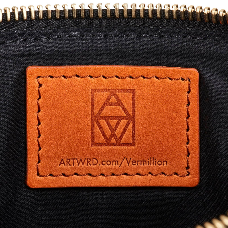 Close up of Italian vegetable tanned leather art pouch label.  This is embossed with a web address for exploring the artist and writer that created this product. 