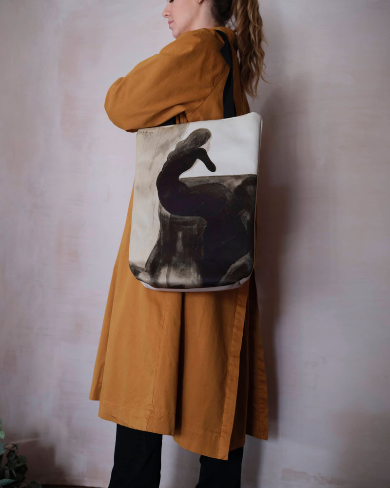 Unique art tote bag displaying a Leon Spilliaert artwork worn by a female model in a burnt orange trench coat.