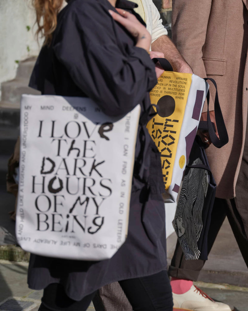 A close up shot of people carrying unique art tote bags on a London street.