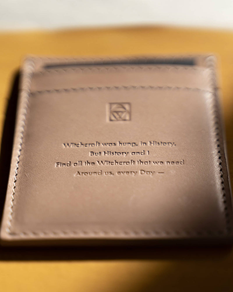 Close up of a unique card holder wallet embossed with an Emily Dickinson witches poem 'Witchcraft Was Hung In History'.