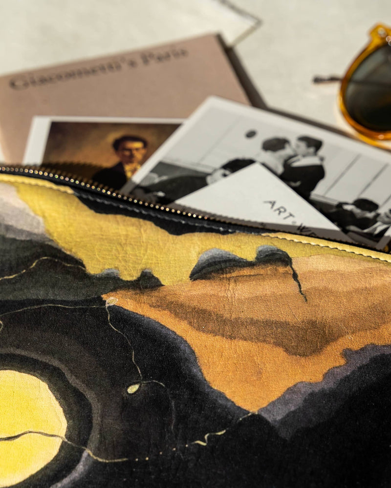 Close up of an unusual bag printed with Arthur Dove 'Me and The Moon' artwork with photos, art guides and arty yellow sunglasses spilling out of it.