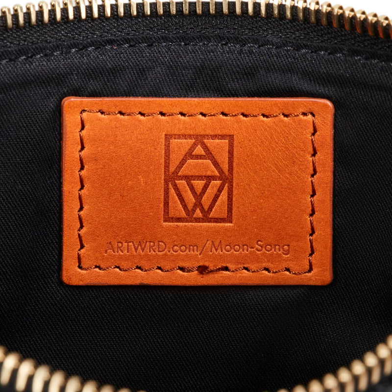 Close up of the unusual bag leather label embossed with the ART WRD logo and an exploration web address for the bag.